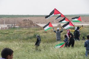 Palestinian youth approach the border fence as Israeli snipers look on from a mound of dirt on the other side, east of Shajaia, Gaza, during the start of the ‘Great Return March.’ March 30, 2017. (+972 Magazine)